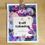 Floral wall calendar for 2026 on a wooden surface