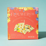 Box of Flower Co artisanal crackers with edible flowers on a light blue background