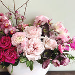 Premium flower arrangement featuring garden roses, orchids and seasonal flowers in shades of pink.