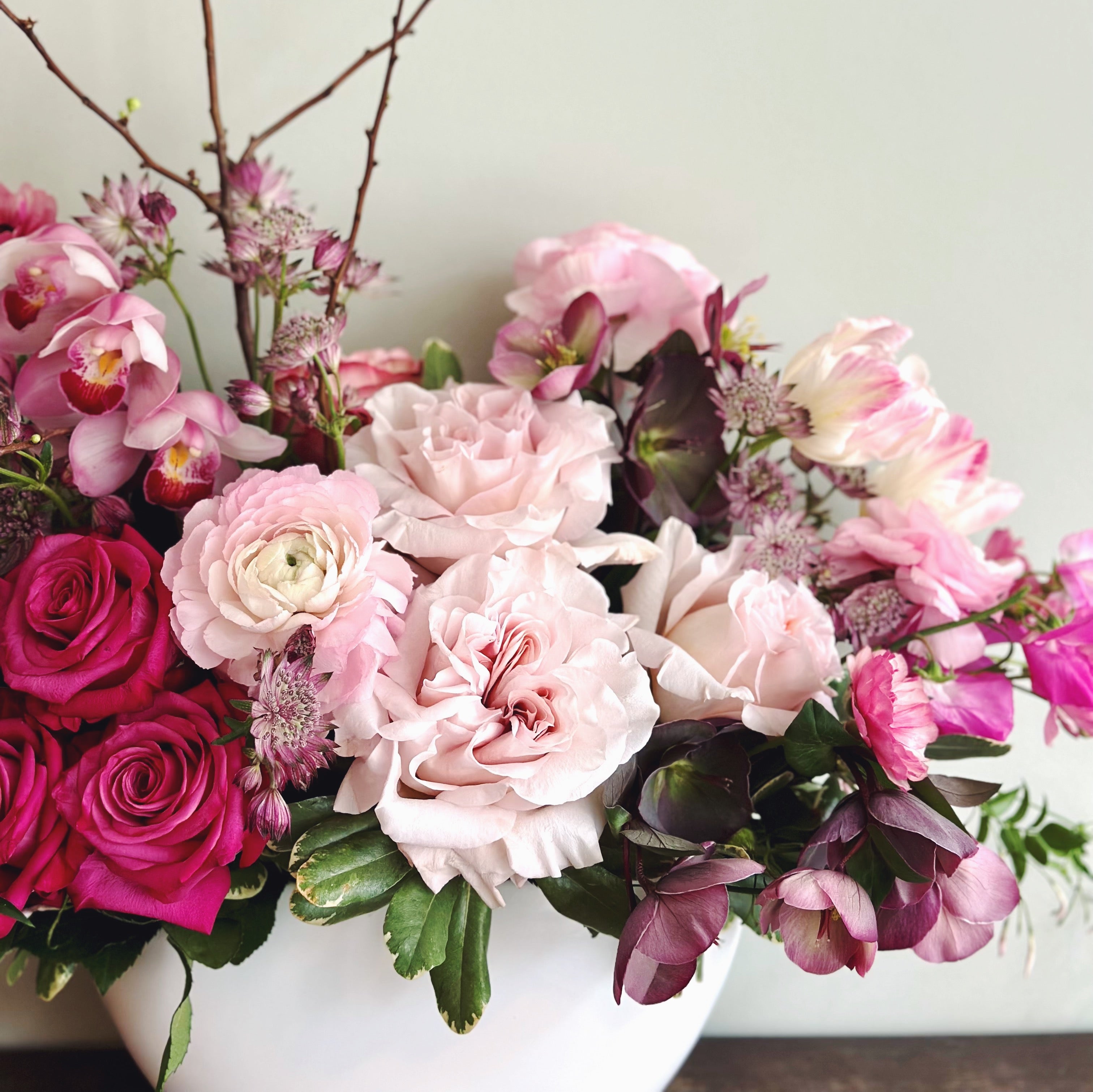 Premium flower arrangement featuring garden roses, orchids and seasonal flowers in shades of pink.