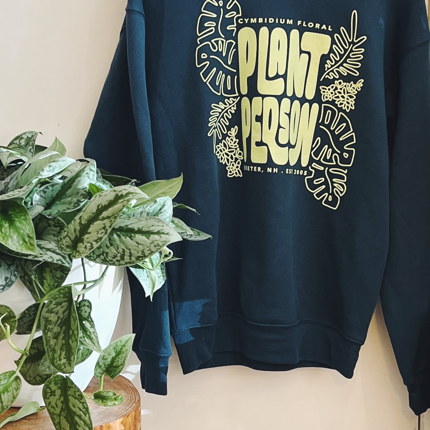 Deep green sweatshirt with 'Plant Person' text and plant designs on a light background