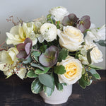 Large lush and low flower arrangement in white, cream, green, and stormy purple.  Roses, ranunculus, astrantia, helleborus, tulips. eucalyptus.