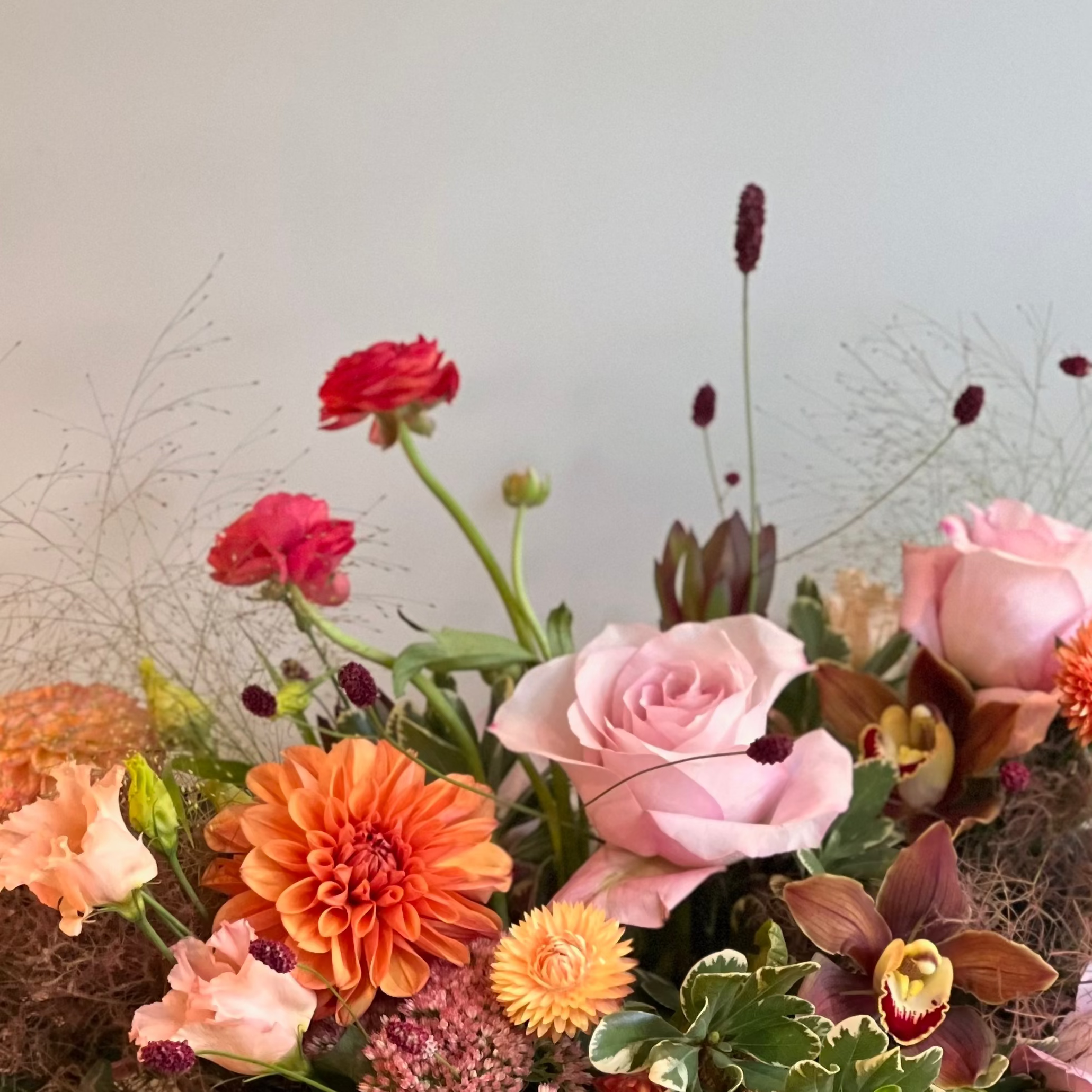 Bouquet of fall colored flowers and natural textures including roses, dahlias, and orchids 