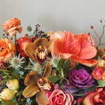 Bouquet of fall colored flowers and natural textures including amaryllis, kale ranunculus, and orchids 