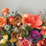 Bouquet of fall colored flowers and natural textures including amaryllis, kale ranunculus, and orchids 
