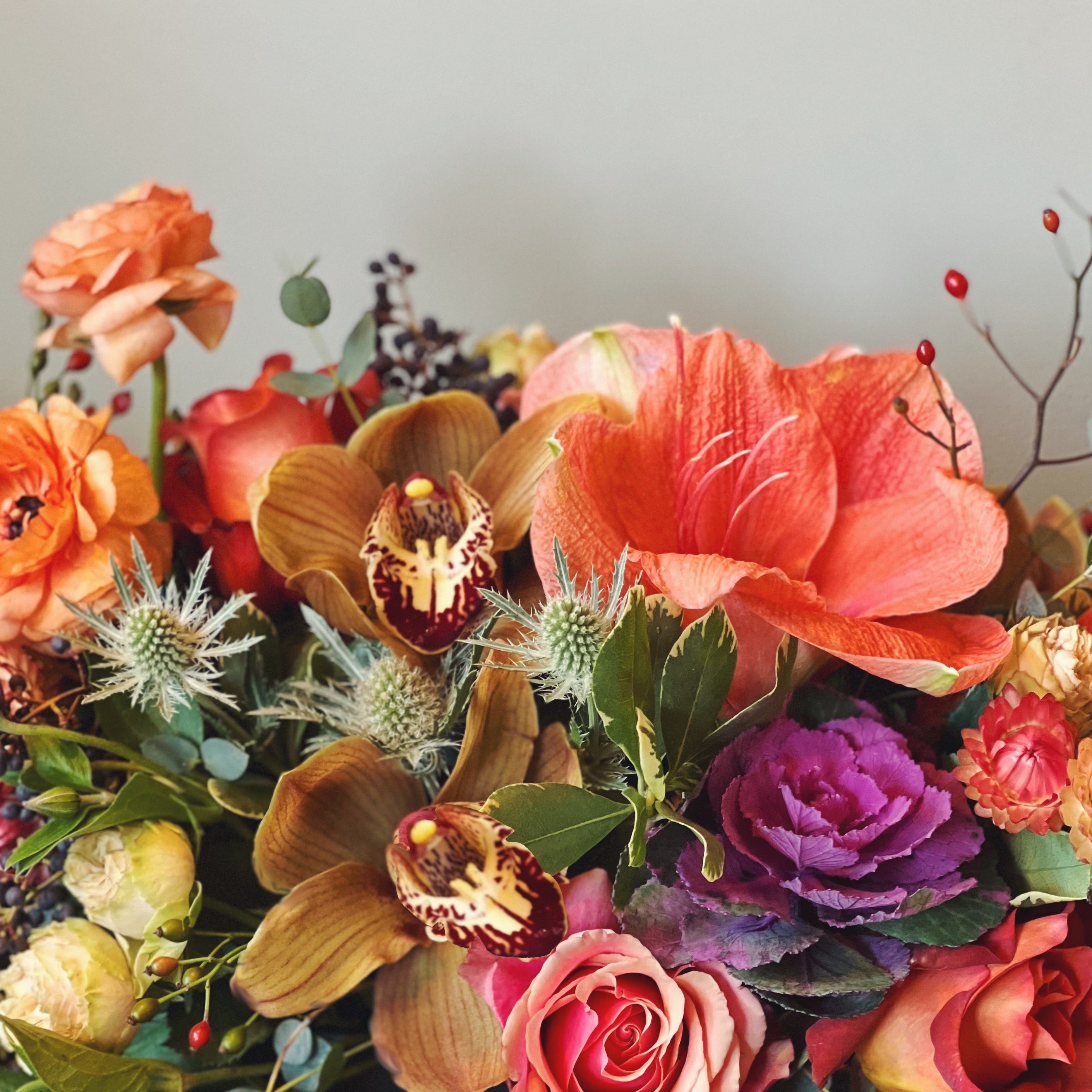Bouquet of fall colored flowers and natural textures including amaryllis, kale ranunculus, and orchids 