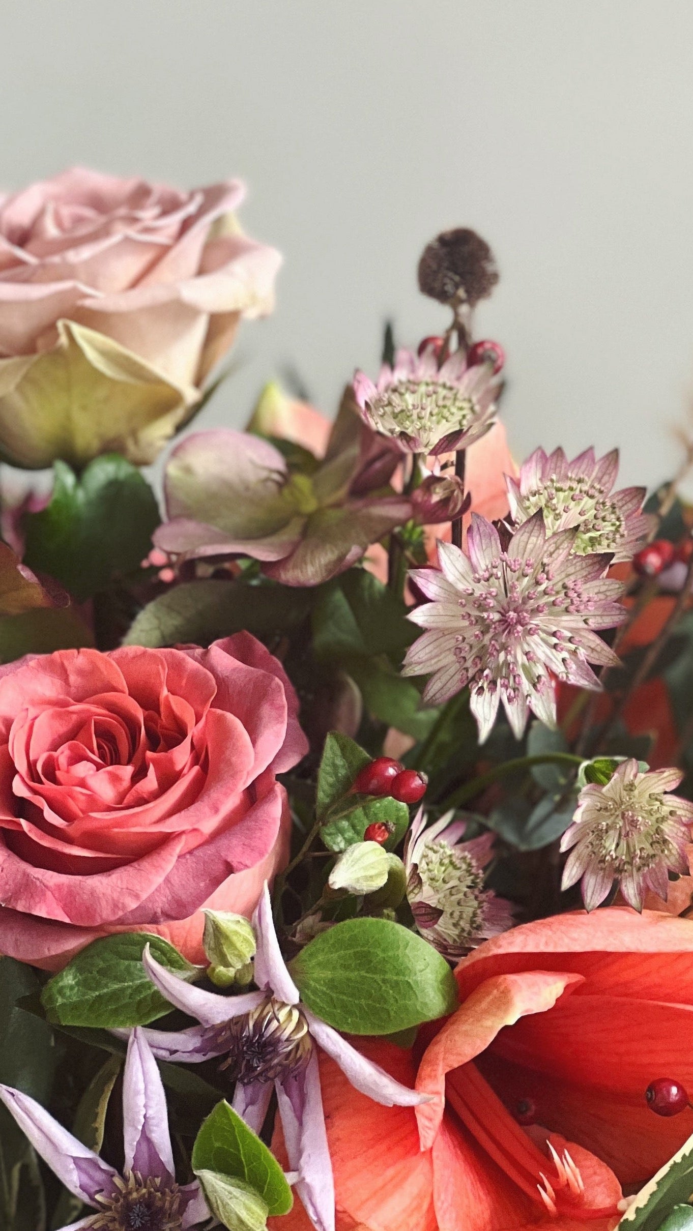 Thanksgiving floral arrangement of soft fall colored flowers and natural textures including roses, amaryllis, clematis and natural textures against a pale green background