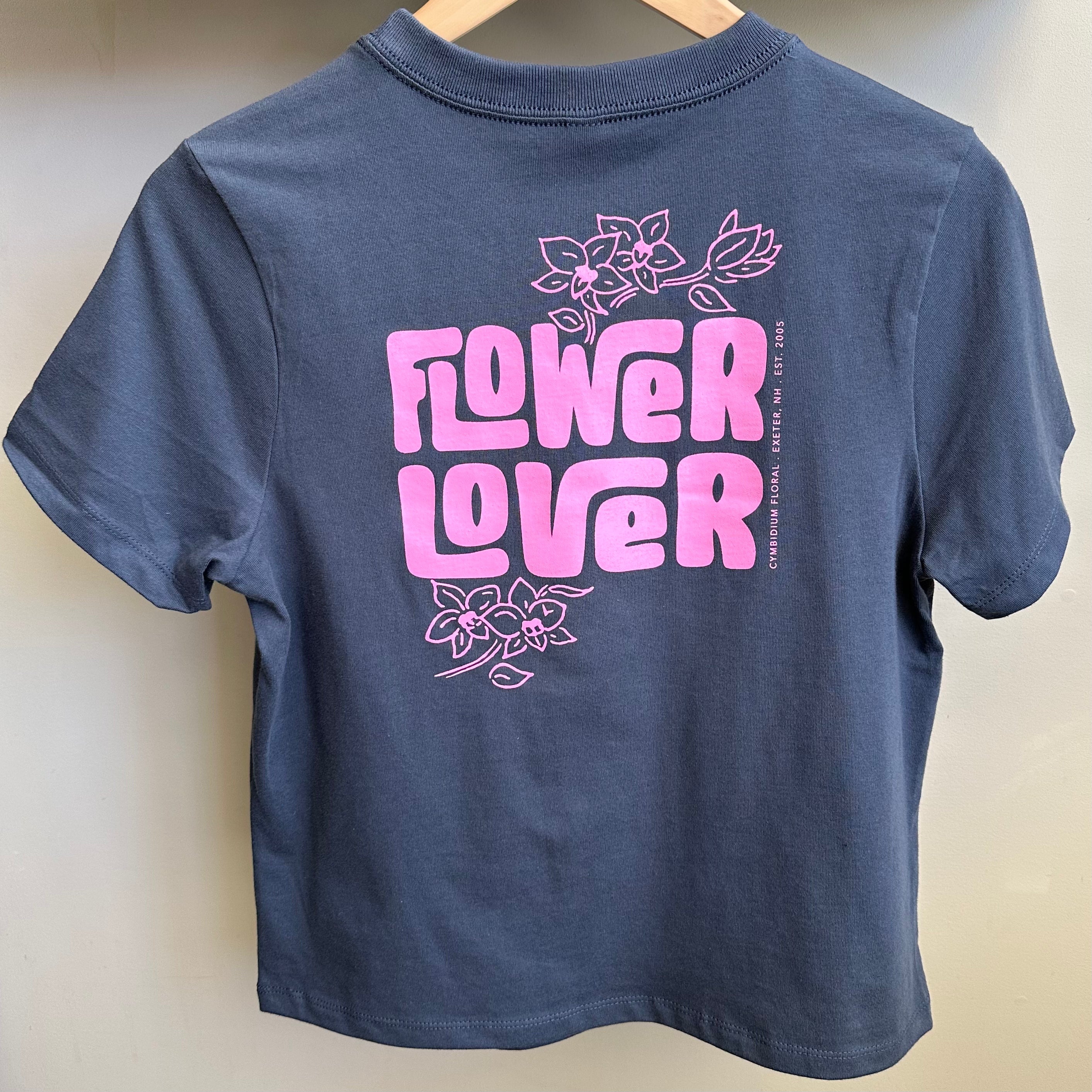 A dark gray boxy women's t-shirt with pink Cymbidium Floral 'FLOWER LOVER' graphic and floral designs printed on the front and back.