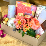 Gift box or basket with premium flowers, gourmet crackers, organic tea, chocolate bars, candle, and floral cocktail cubes.