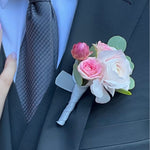 White and pink floral prom boutonniere on a dark suit jacket with a light blue shirt and gray tie.