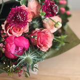 Bouquet of pink, coral and red flowers wrapped in paper for presentation. 