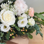 Bouquet of white and pink flowers wrapped in paper.
