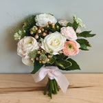 Handheld prom bouquet of white and pink flowers wrapped with ribbon. 