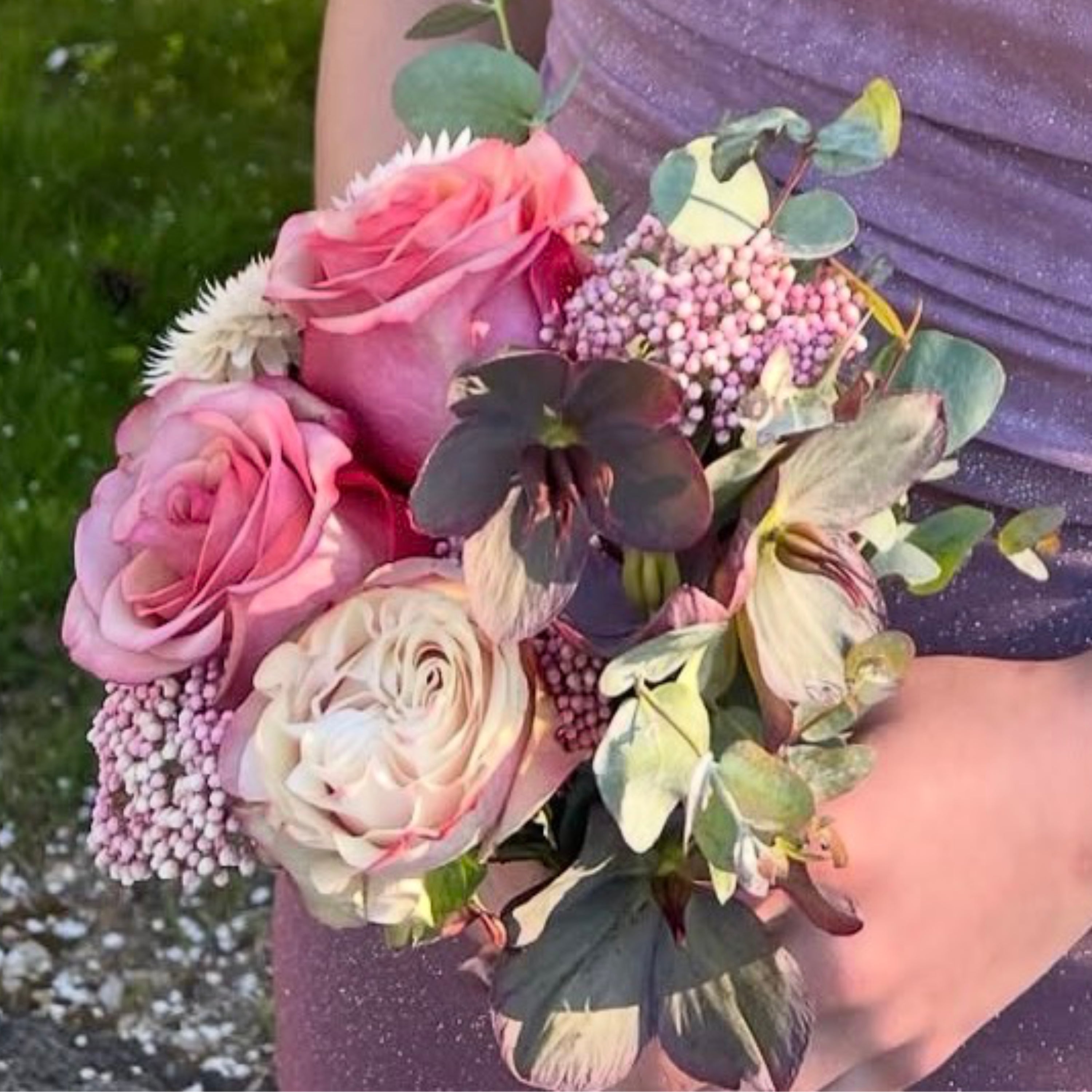 Bouquet of pink and white flowers held by a person outdoors.