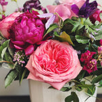 Close up of rich and romantic flower arrangement in pink, purple, and magenta.  Roses, allium, anemones, peony, calla lily.