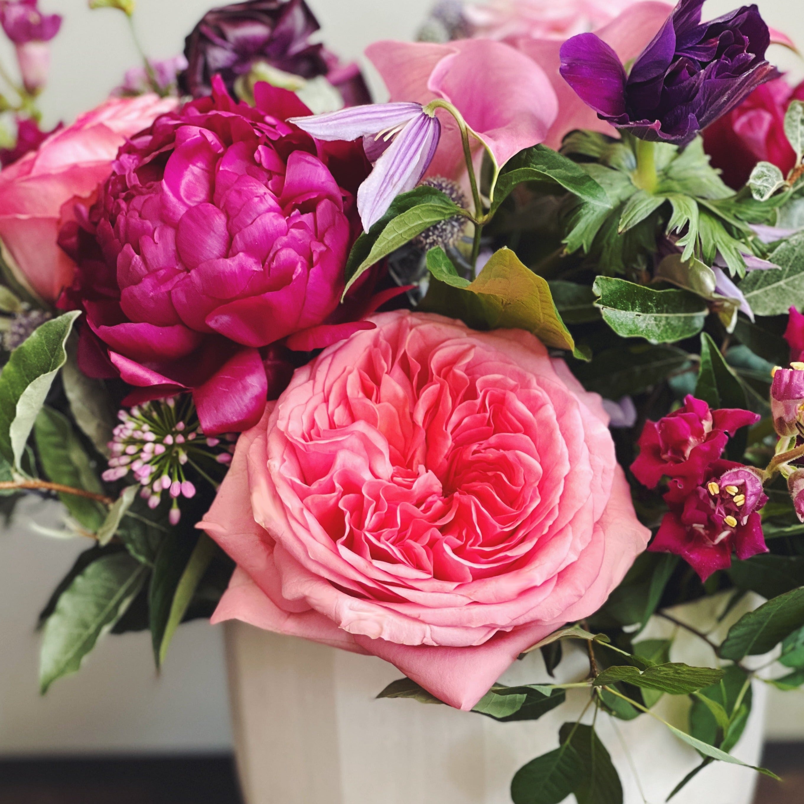 Close up of rich and romantic flower arrangement in pink, purple, and magenta.  Roses, allium, anemones, peony, calla lily.