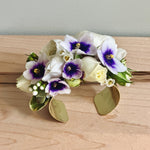 Prom corsage cuff with white and purple flowers on a wooden surface