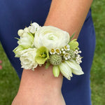 Floral wrist corsage cuff on a person's wrist with a blurred background