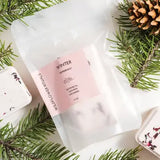 White shower steamers with pink labels on a white surface with pine branches